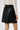 Side view of black leather mini skirt highlighting soft structure and gentle A-line shape.